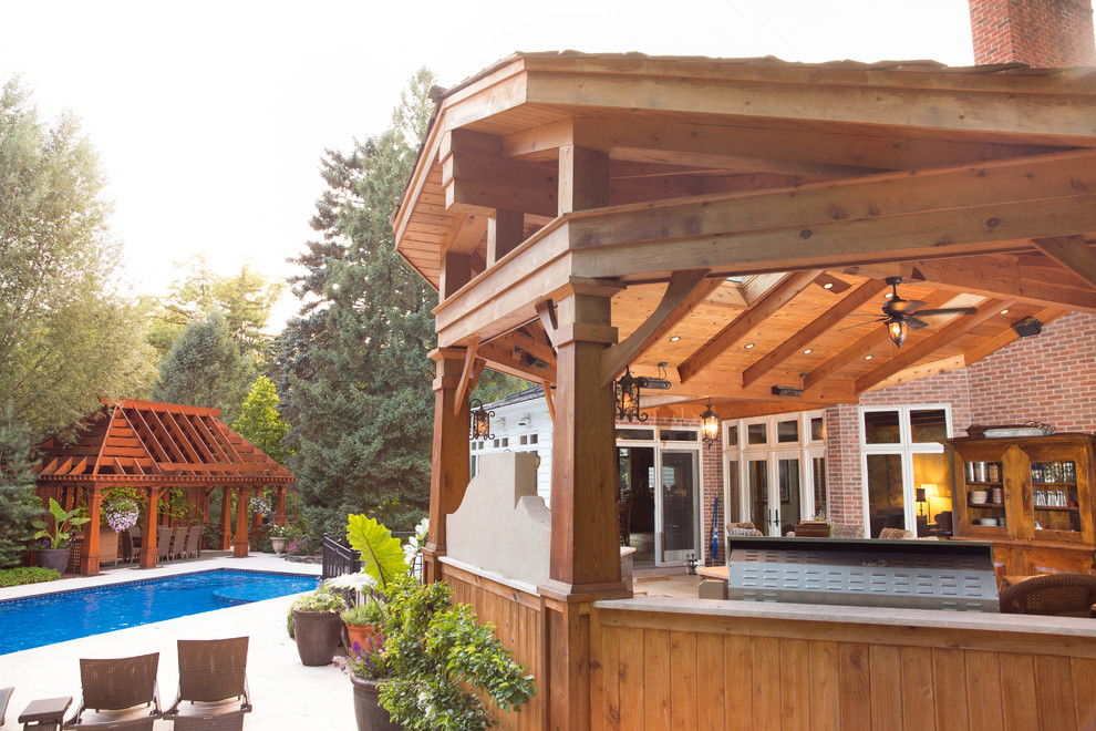 Inspiration for a large timeless backyard stone patio remodel in Chicago with a fire pit and a roof extension