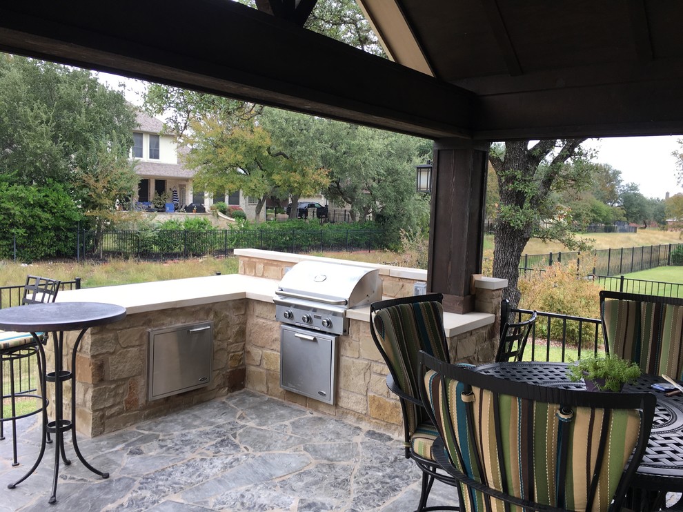 Großer, Überdachter Rustikaler Patio hinter dem Haus mit Outdoor-Küche und Natursteinplatten in Austin