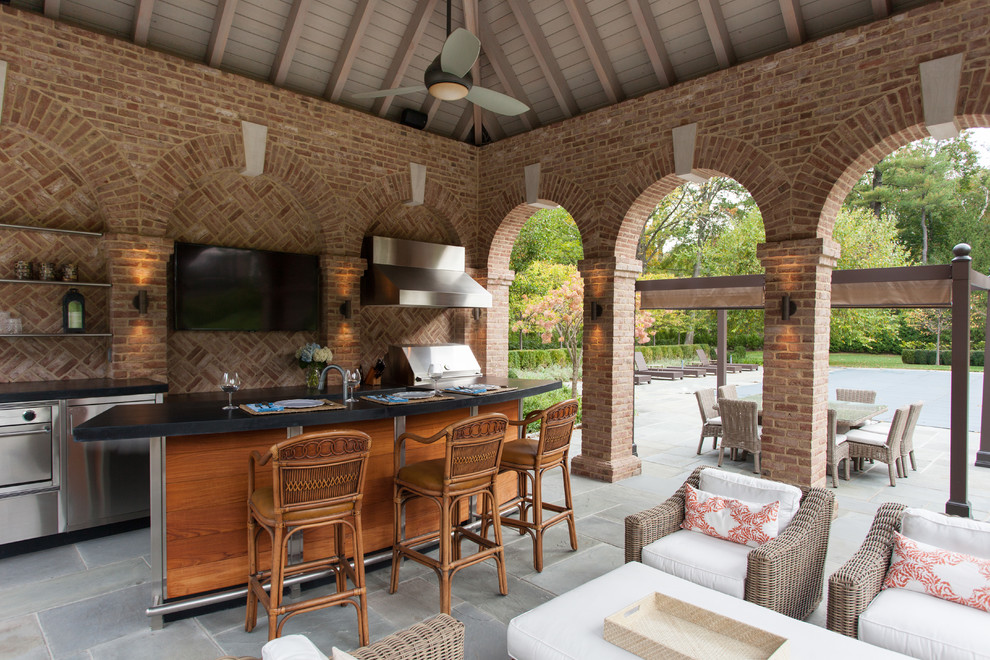 Cette image montre une très grande terrasse arrière traditionnelle avec une cuisine d'été, des pavés en pierre naturelle et un gazebo ou pavillon.