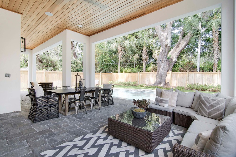 Example of a large beach style backyard concrete paver patio design in Orlando with a roof extension