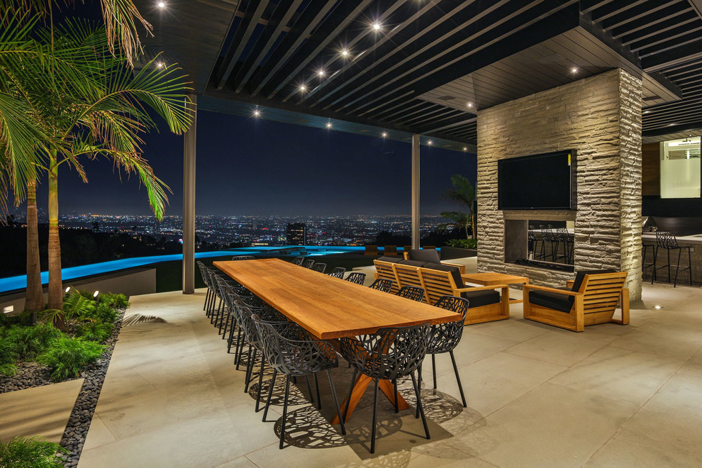 ロサンゼルスにある広いコンテンポラリースタイルのおしゃれな裏庭のテラス (コンクリート板舗装	、張り出し屋根、屋外暖炉) の写真