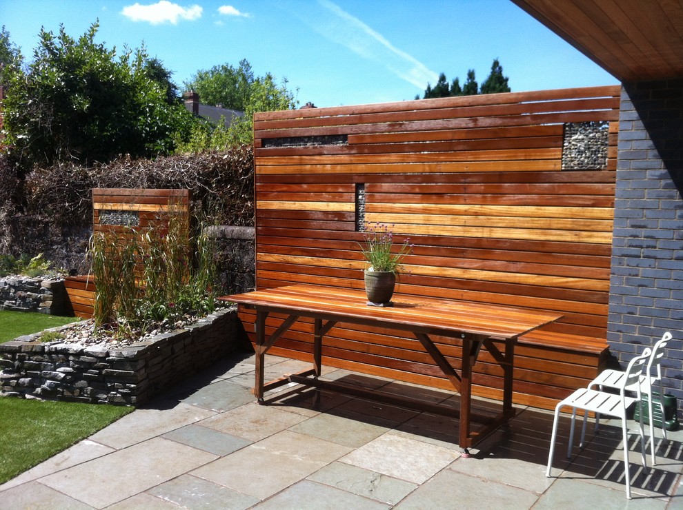Cette image montre un mur végétal de terrasse arrière design de taille moyenne avec des pavés en béton et une extension de toiture.