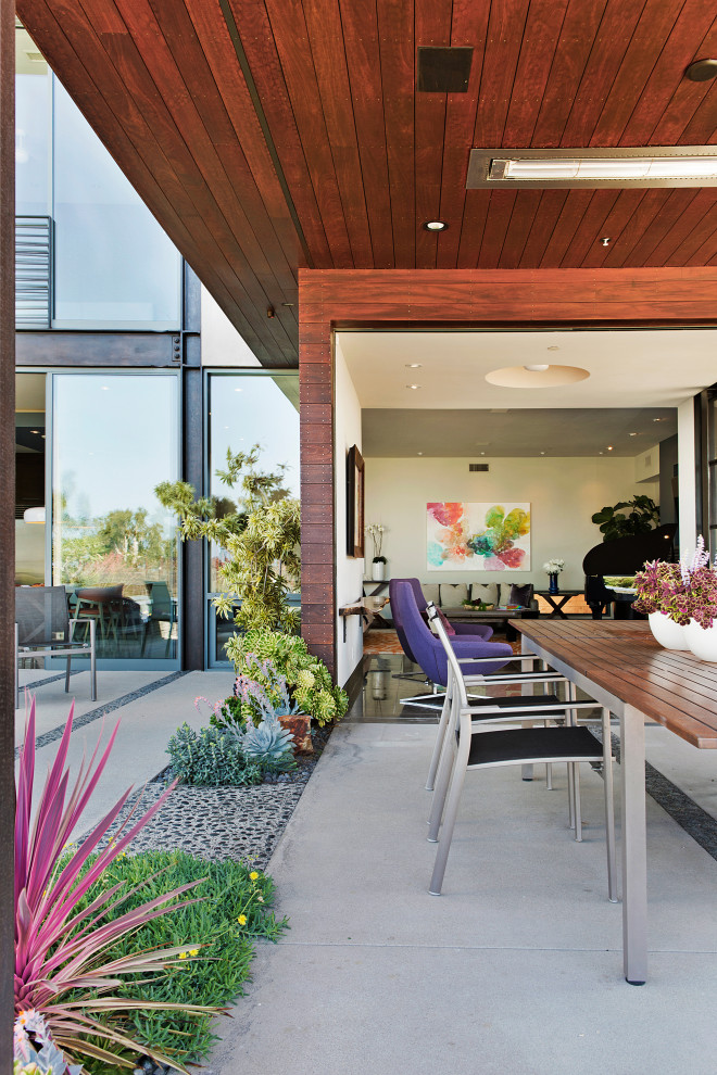 На фото: большой двор на заднем дворе в современном стиле с летней кухней, покрытием из бетонных плит и навесом