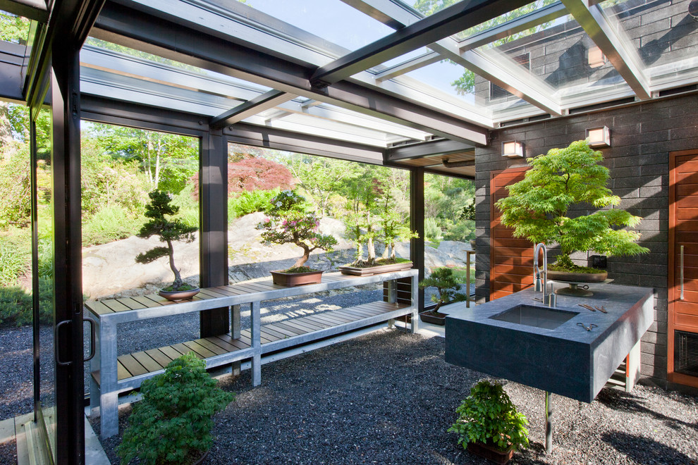 Aménagement d'une petite terrasse arrière moderne avec un foyer extérieur, du gravier et une extension de toiture.