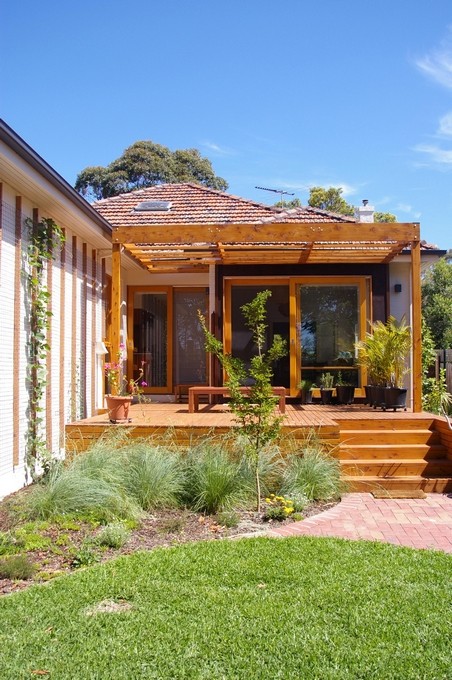 Inspiration för en mellanstor funkis uteplats på baksidan av huset, med en vertikal trädgård, trädäck och en pergola