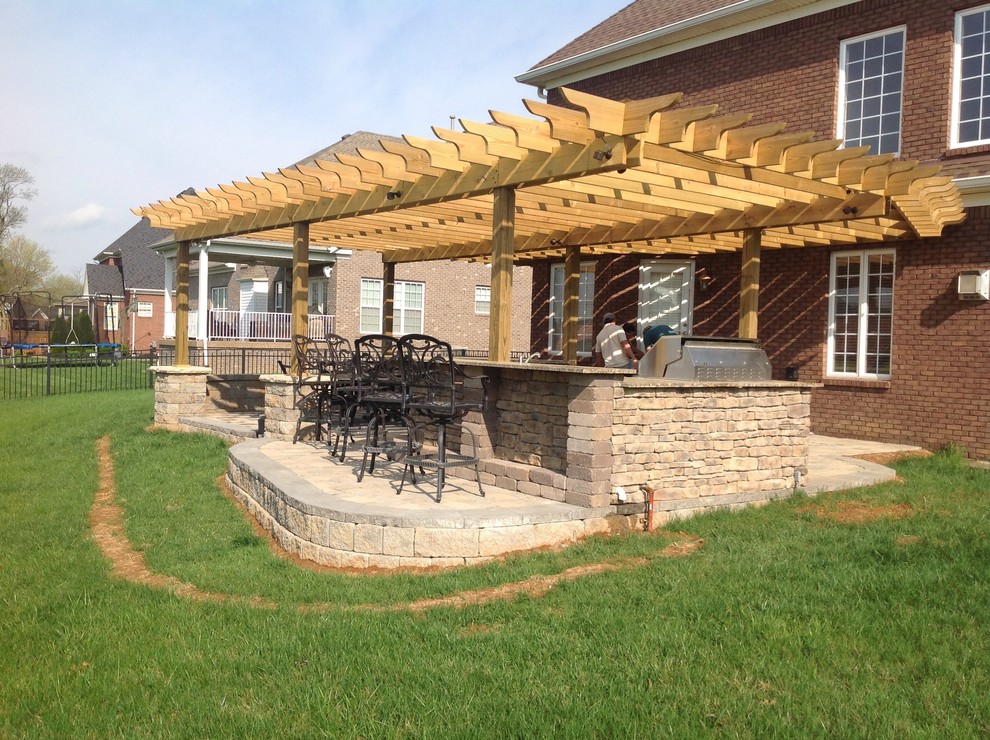 Inspiration for a large timeless backyard concrete paver patio kitchen remodel in Louisville with a pergola