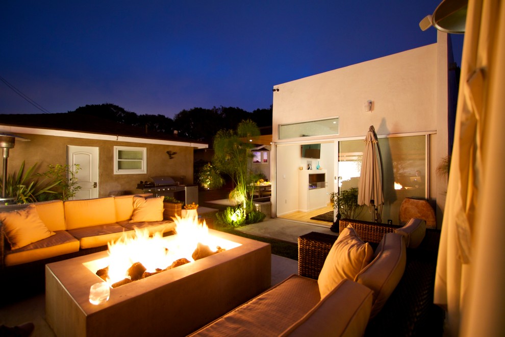 Photo of a large contemporary back patio in Los Angeles with a fire feature, concrete slabs and no cover.