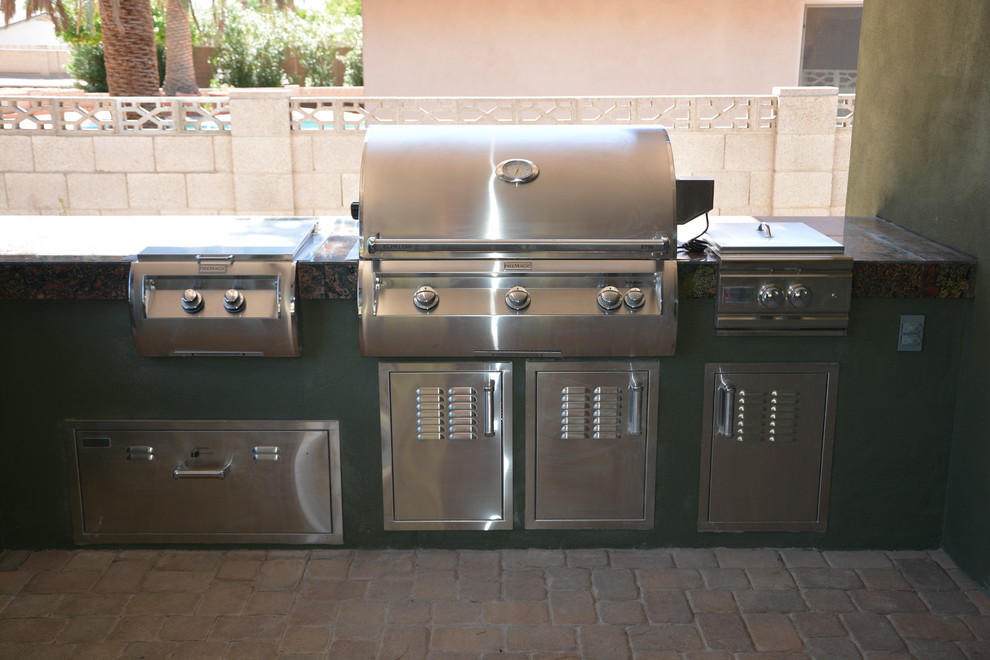 This is an example of a medium sized back patio in Phoenix with an outdoor kitchen and concrete paving.