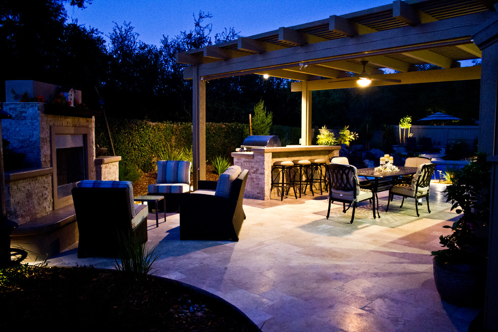 Modelo de patio tradicional grande en patio trasero con adoquines de piedra natural, cocina exterior y pérgola