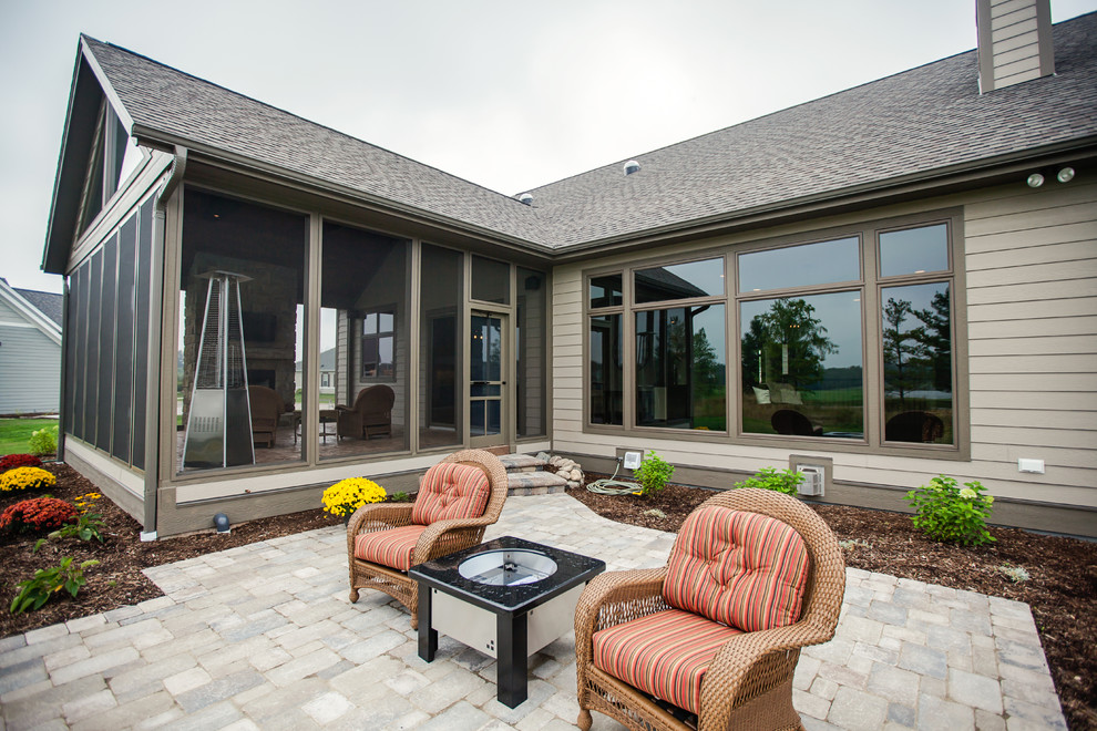 Cette image montre une terrasse traditionnelle avec un foyer extérieur, des pavés en brique et une extension de toiture.