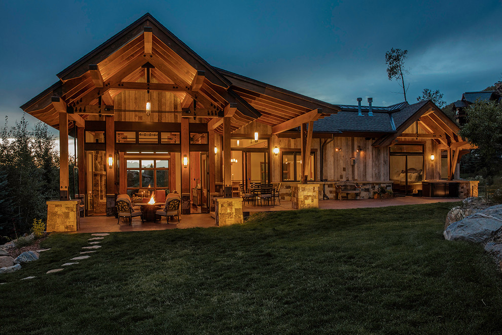 Example of a large trendy backyard stamped concrete patio design in Denver with a fire pit and a roof extension