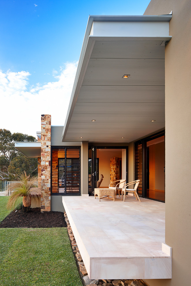 Immagine di un patio o portico minimalista di medie dimensioni e davanti casa con pavimentazioni in pietra naturale e un tetto a sbalzo