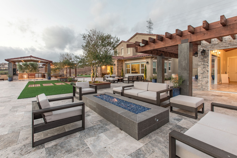 Inspiration for a large contemporary back patio in San Diego with a fire feature, natural stone paving and a pergola.