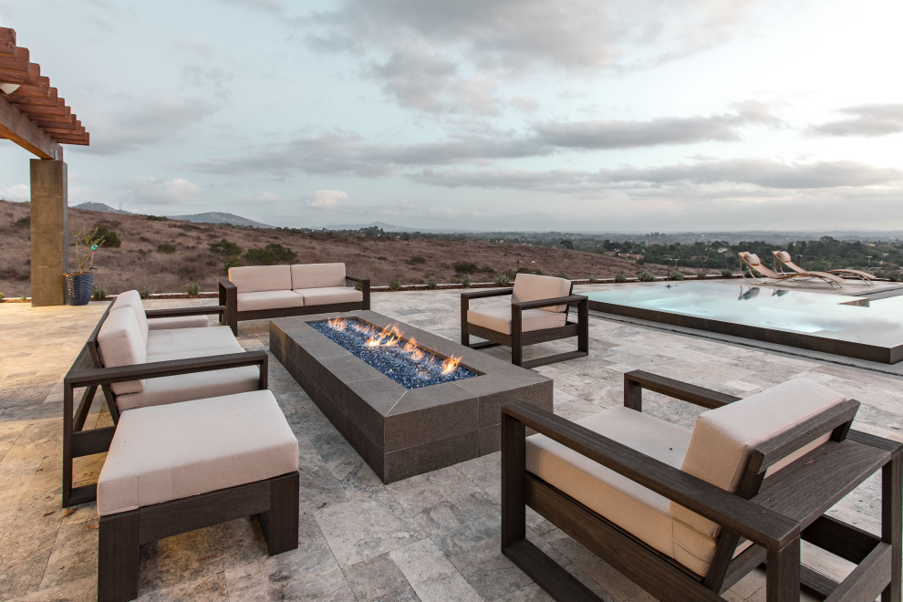 Inspiration for a large contemporary backyard stone patio remodel in San Diego with a pergola and a fire pit