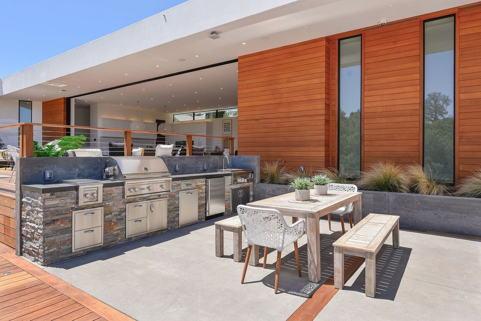 Idée de décoration pour une terrasse arrière design avec une cuisine d'été, une dalle de béton et aucune couverture.
