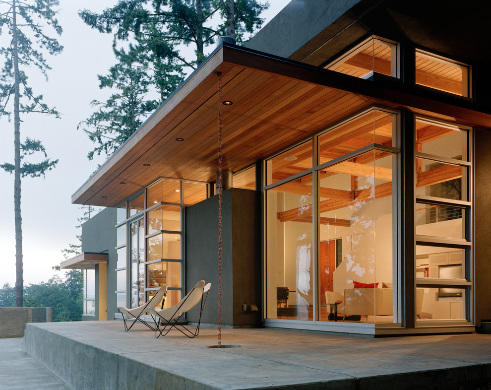 Réalisation d'une terrasse arrière minimaliste de taille moyenne avec une dalle de béton et une extension de toiture.