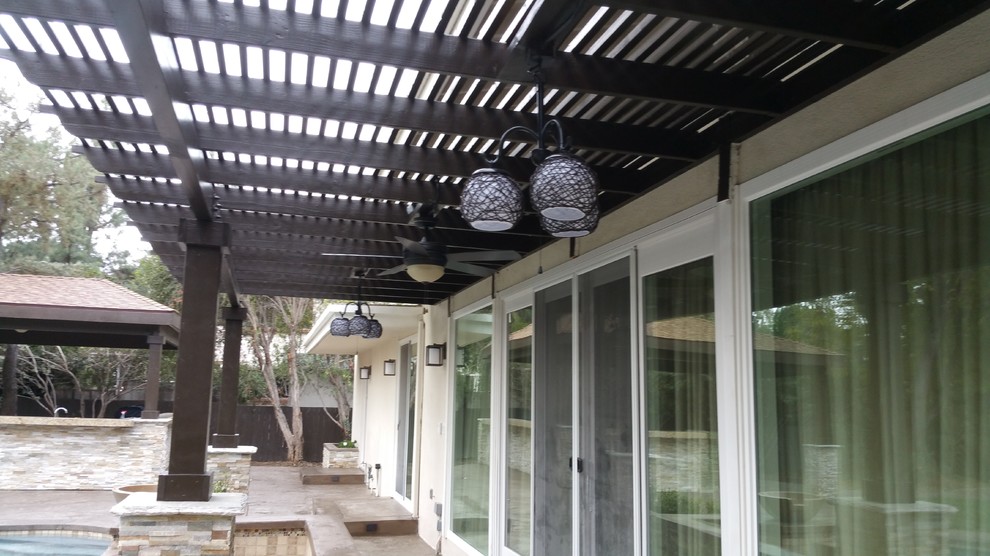 Foto de patio moderno de tamaño medio en patio trasero con cocina exterior, pérgola y adoquines de piedra natural