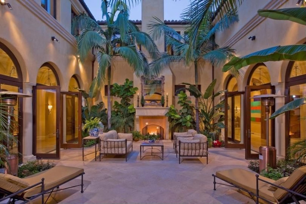 This is an example of an expansive mediterranean courtyard patio in Other with natural stone paving, a fire feature and no cover.