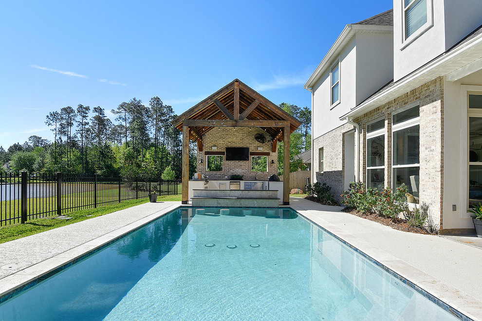 Example of a large transitional backyard stamped concrete pool design in New Orleans
