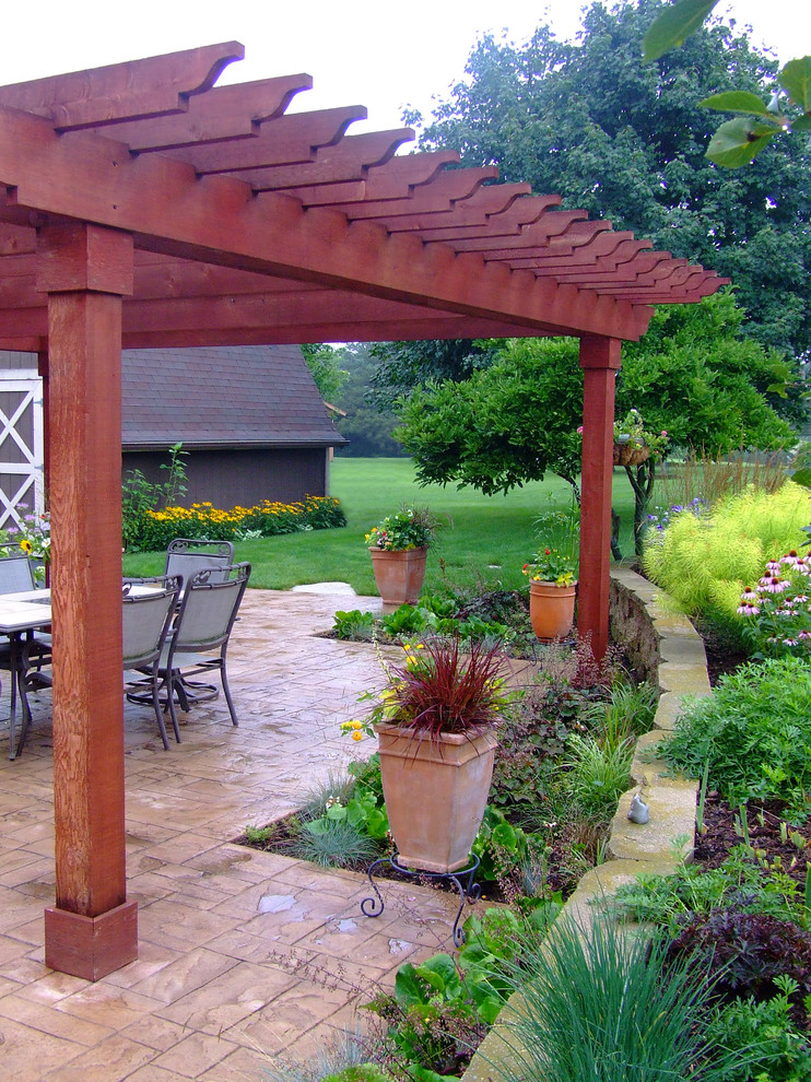 Foto de patio clásico de tamaño medio en patio trasero con suelo de hormigón estampado y pérgola