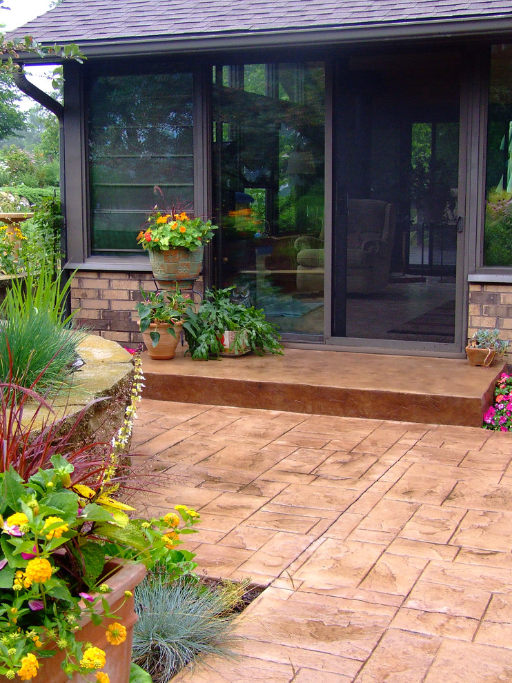 Medium sized traditional back patio in Milwaukee with stamped concrete and a pergola.