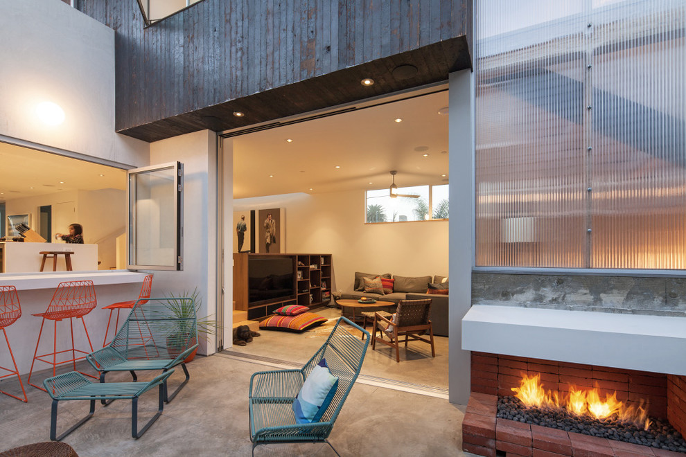 Cette image montre une terrasse arrière minimaliste de taille moyenne avec aucune couverture et un foyer extérieur.