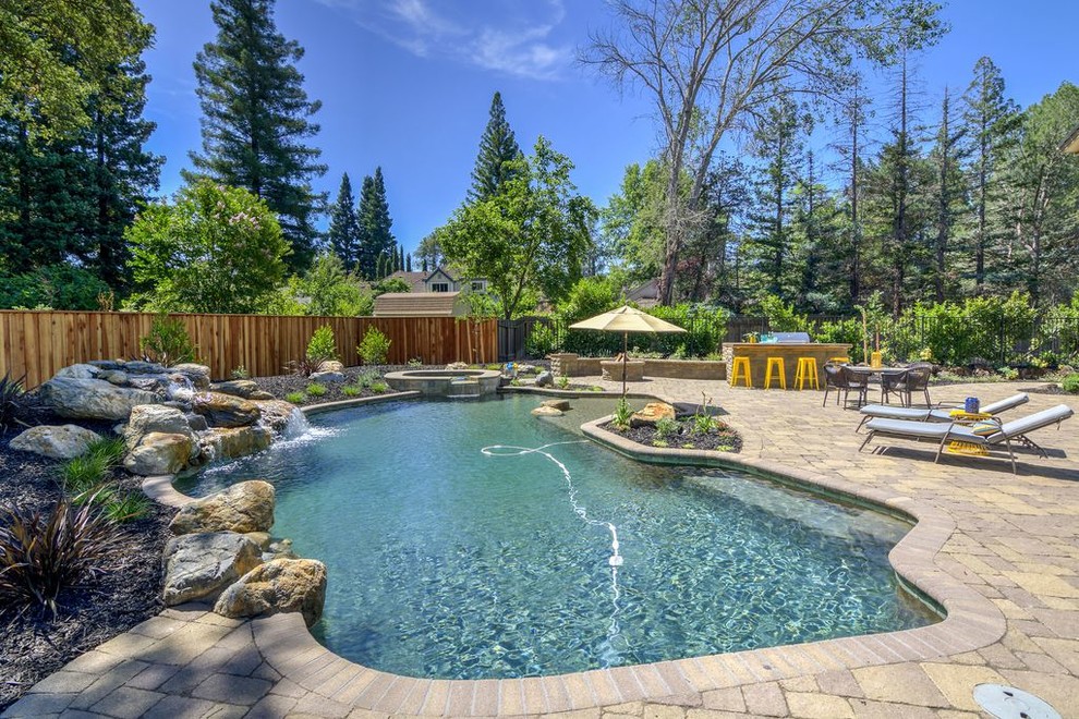 This is an example of a large traditional back swimming pool in Sacramento with concrete paving.