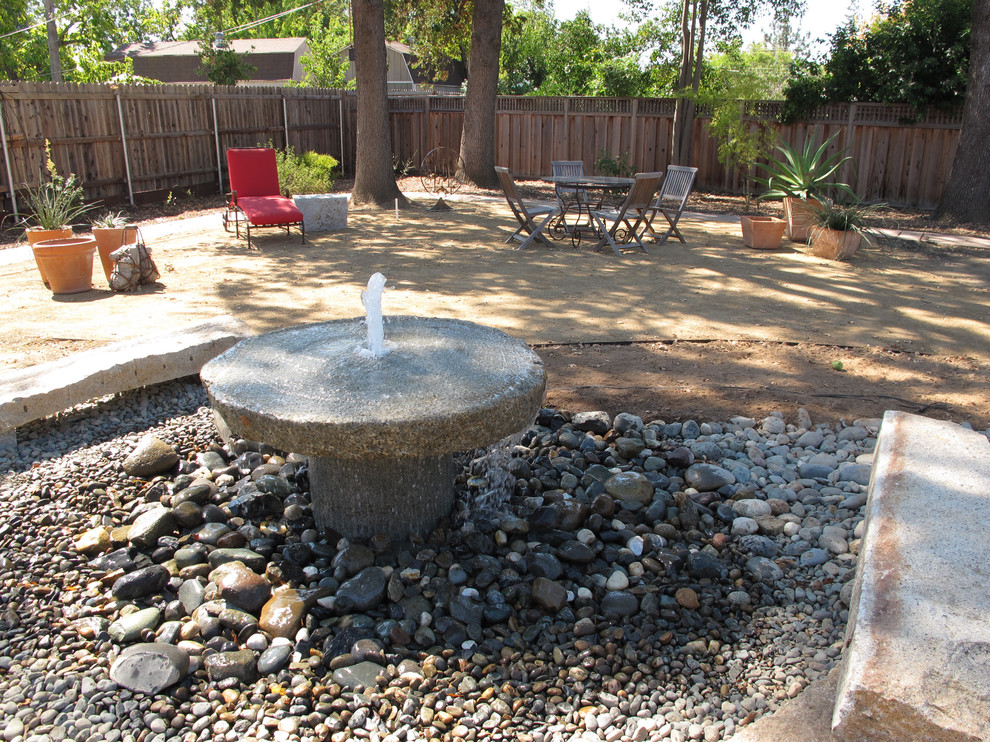 Moderner Patio hinter dem Haus mit Wasserspiel und Granitsplitt in Sacramento
