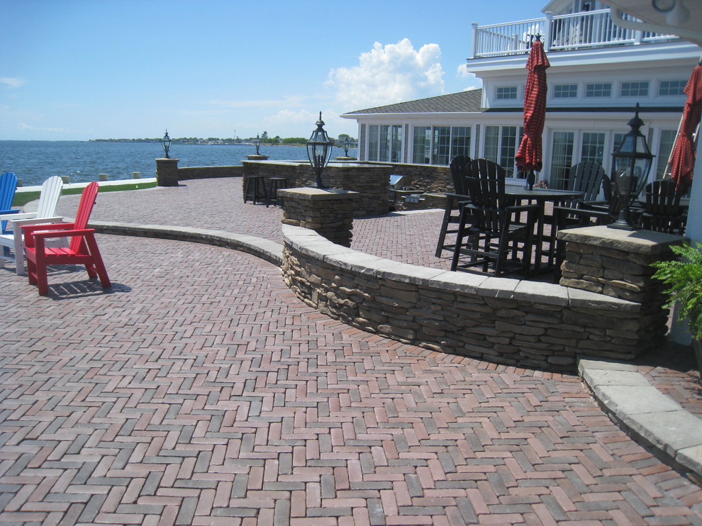 Cette image montre une grande terrasse arrière marine avec une cuisine d'été, des pavés en béton et une pergola.
