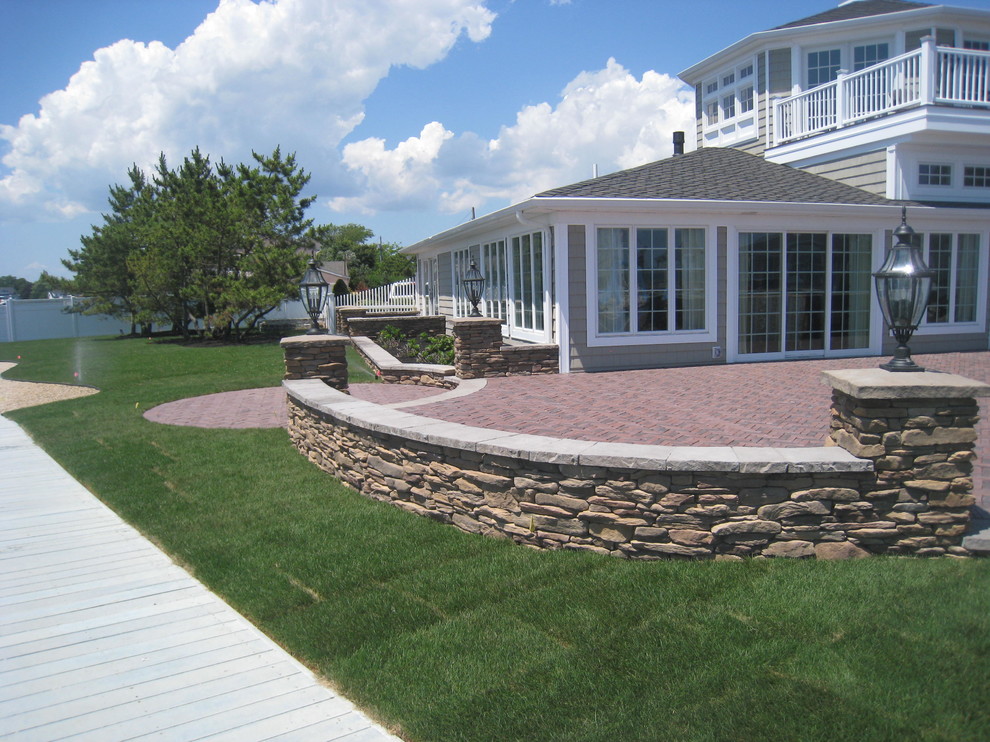 Large coastal back patio in New York with an outdoor kitchen, concrete paving and a pergola.