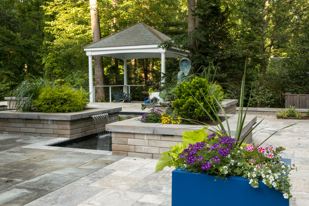 Inspiration pour une terrasse avec des plantes en pots arrière design de taille moyenne avec des pavés en pierre naturelle et une pergola.