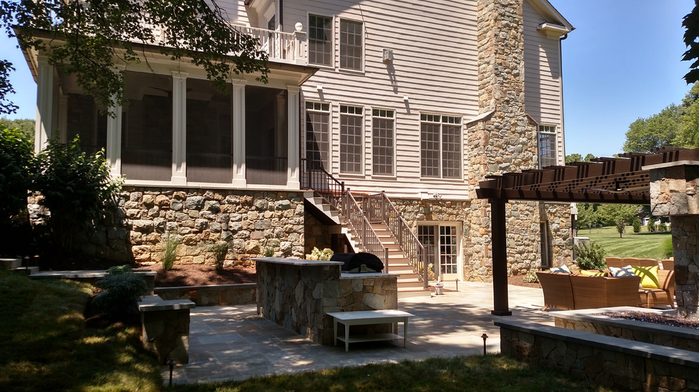 Imagen de patio clásico renovado grande en patio trasero con brasero, adoquines de piedra natural y pérgola