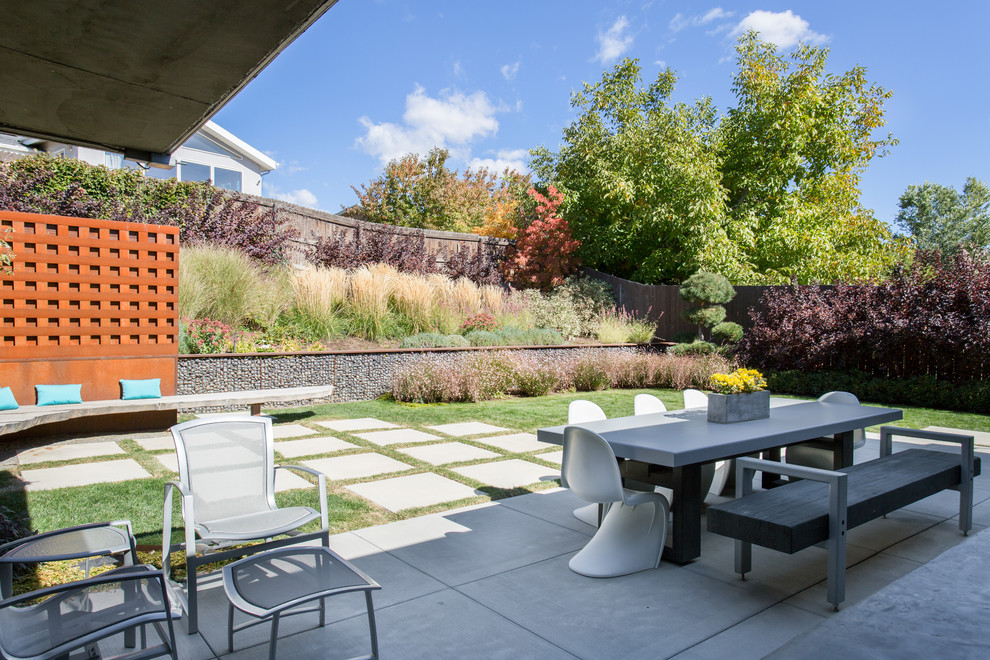 Mid-sized 1950s backyard concrete paver patio photo in Salt Lake City with a roof extension