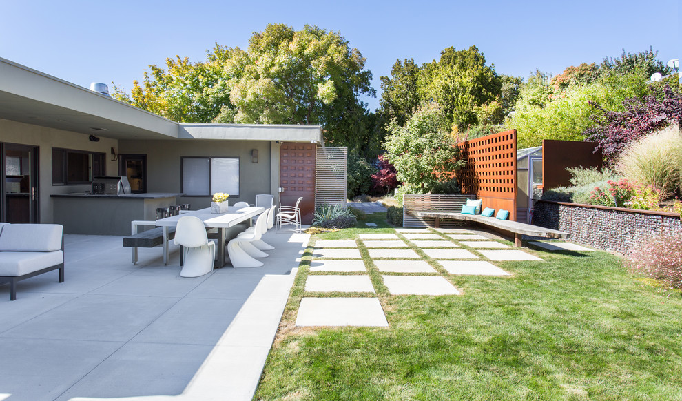 Foto di un patio o portico minimalista di medie dimensioni e dietro casa con pavimentazioni in cemento e un tetto a sbalzo