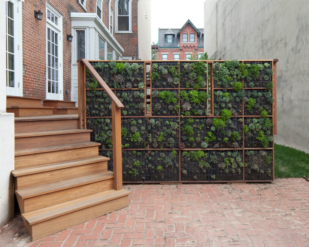 Diseño de patio actual sin cubierta con jardín vertical y adoquines de ladrillo