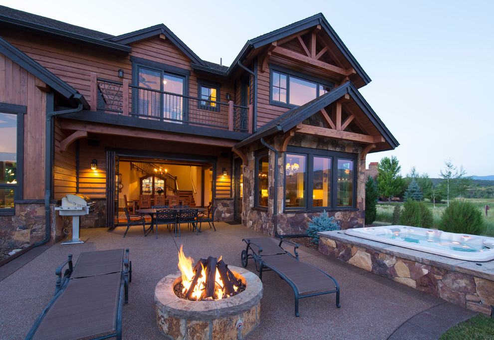 Patio - large rustic backyard stone patio idea in Denver with a fire pit and a roof extension