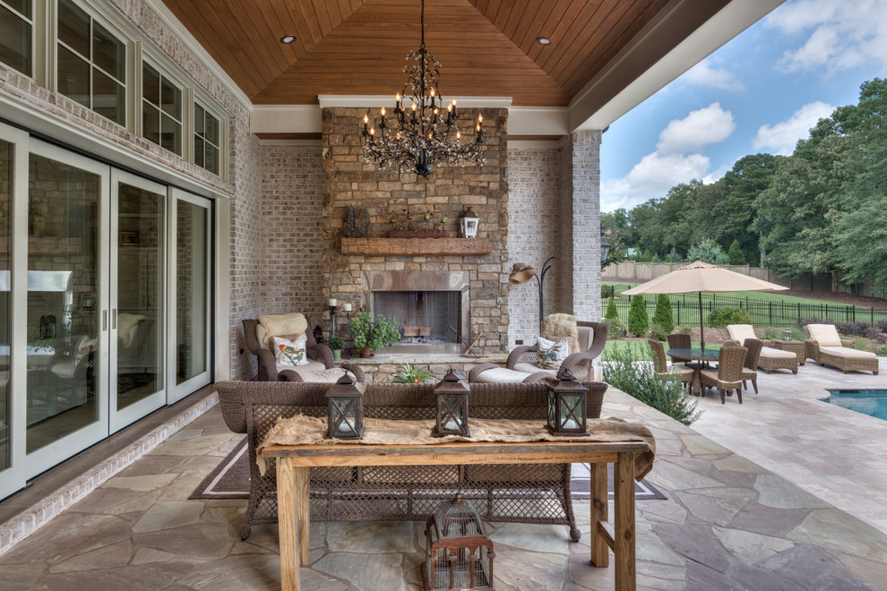 Large mountain style backyard stone patio photo in Other with a roof extension and a fireplace