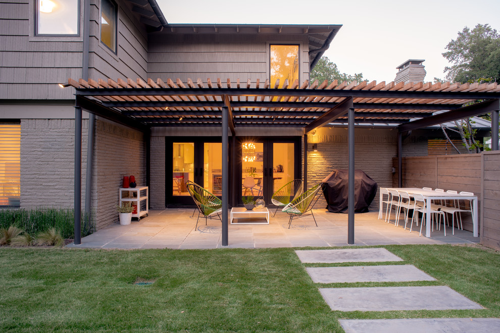 This is an example of a medium sized contemporary back patio in Dallas with concrete slabs and a pergola.