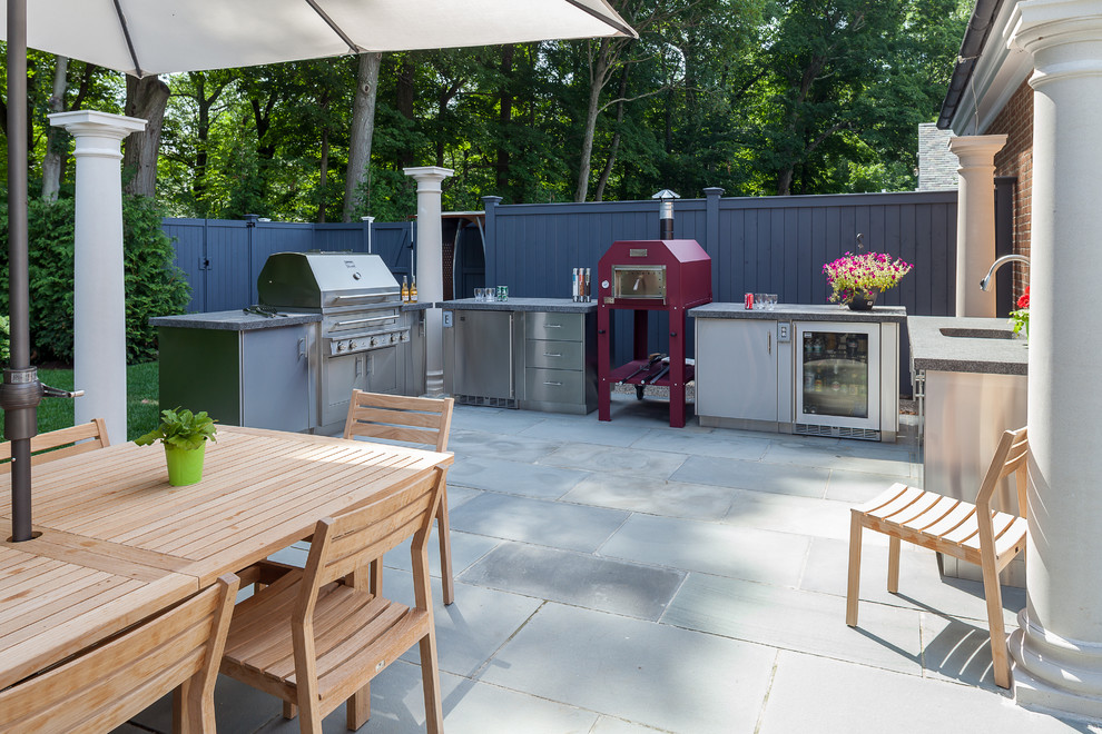 Idée de décoration pour une terrasse arrière design de taille moyenne avec une cuisine d'été, des pavés en pierre naturelle et une pergola.