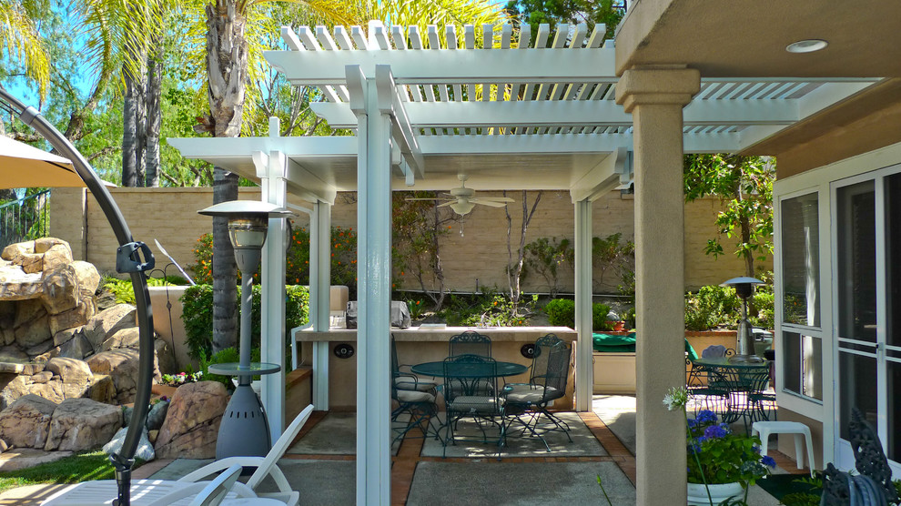 Immagine di un patio o portico tradizionale di medie dimensioni e dietro casa con fontane, lastre di cemento e una pergola