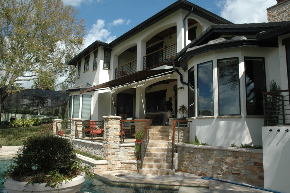 This is an example of a large classic back patio in Orlando with an outdoor kitchen and an awning.