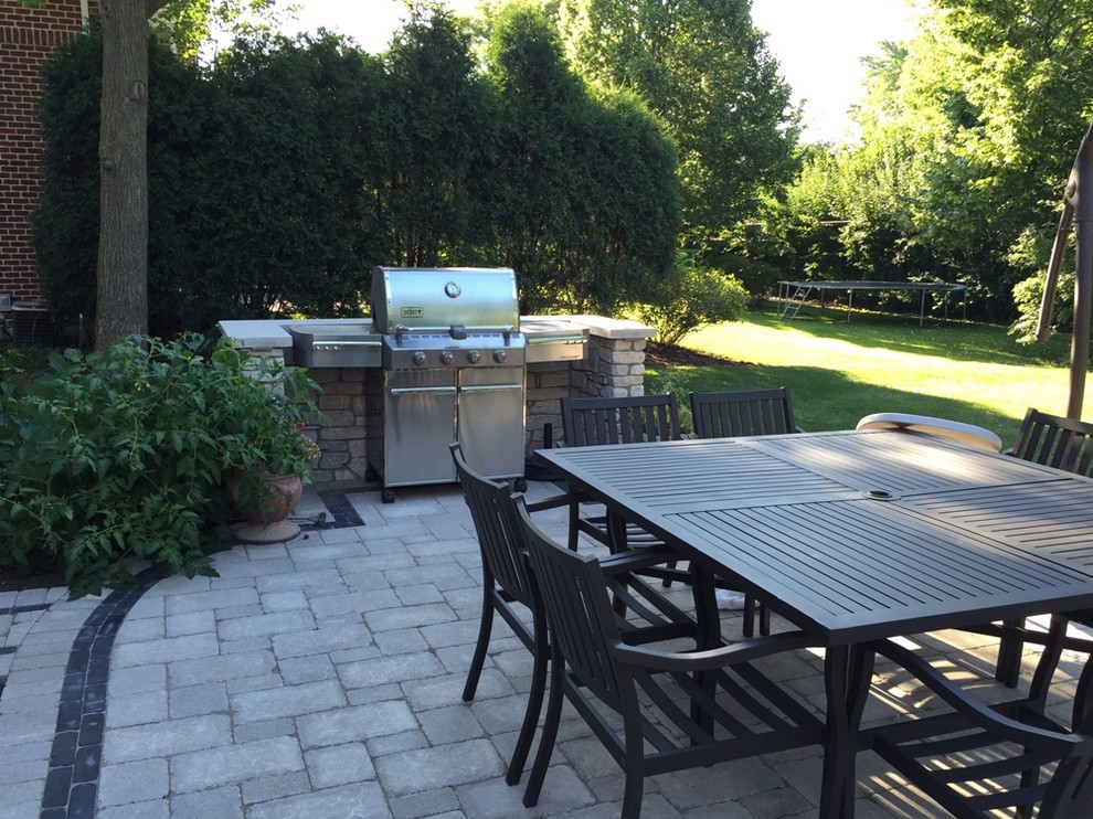 Medium sized classic back patio in Chicago with an outdoor kitchen, natural stone paving and no cover.