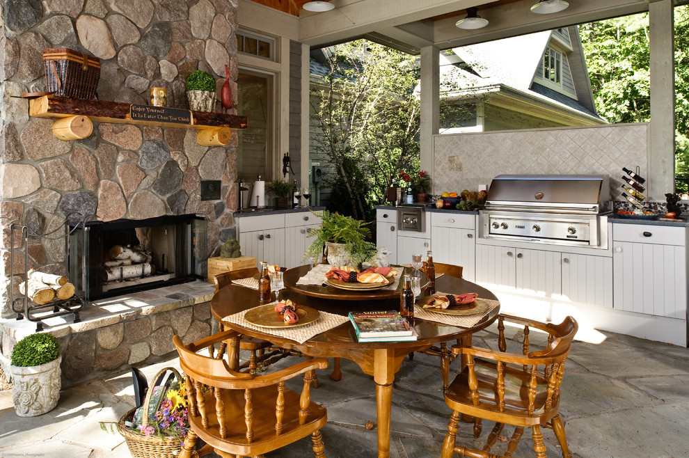 Großer, Überdachter Rustikaler Patio hinter dem Haus mit Outdoor-Küche und Natursteinplatten in Sonstige