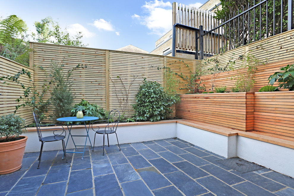 Inspiration for a medium sized contemporary back patio in London with natural stone paving.