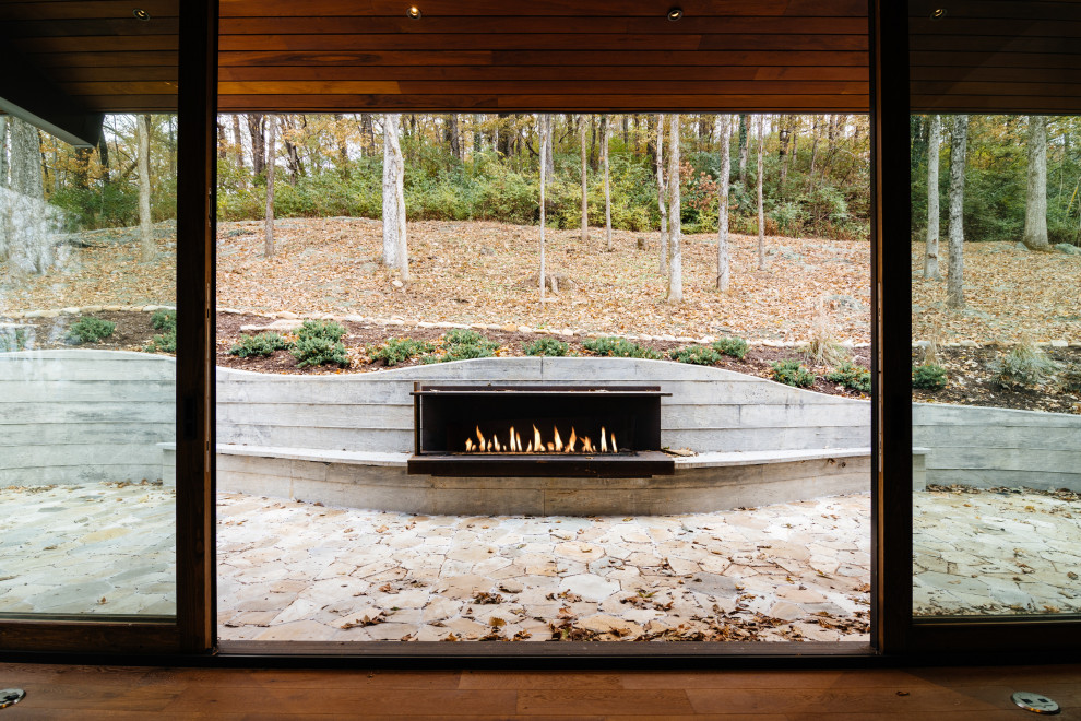 Ejemplo de patio moderno de tamaño medio sin cubierta en patio trasero con chimenea y adoquines de piedra natural