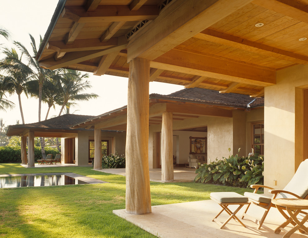 Idee per un patio o portico tropicale con un tetto a sbalzo