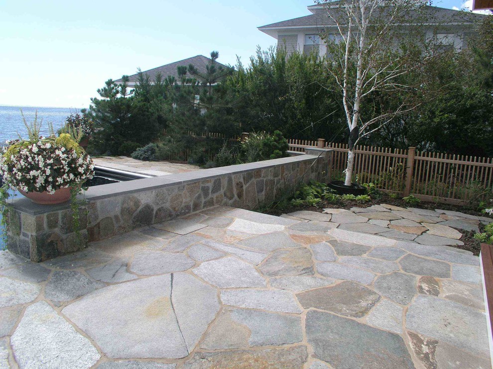Immagine di un patio o portico costiero dietro casa con pavimentazioni in pietra naturale e nessuna copertura