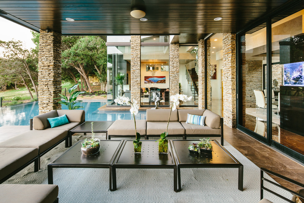 Patio - large mid-century modern backyard patio idea in Austin with a roof extension