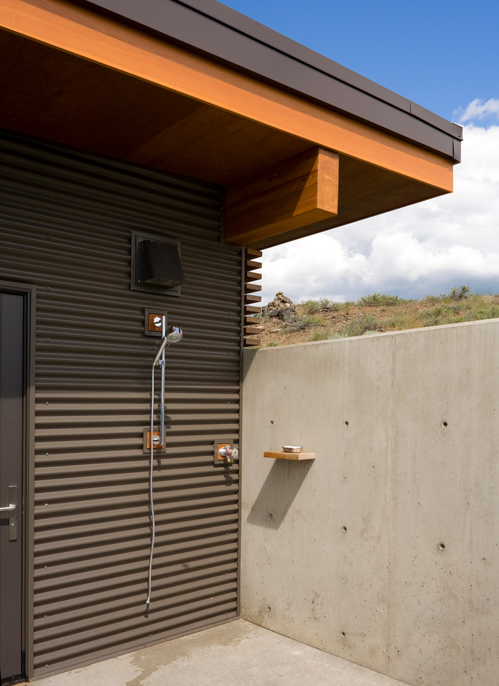 Cette photo montre une terrasse avec une douche extérieure arrière tendance avec une dalle de béton et une extension de toiture.