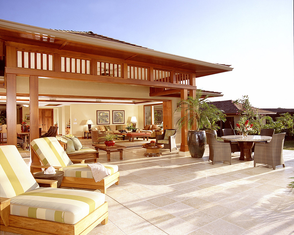 Immagine di un grande patio o portico tropicale dietro casa con piastrelle e un tetto a sbalzo